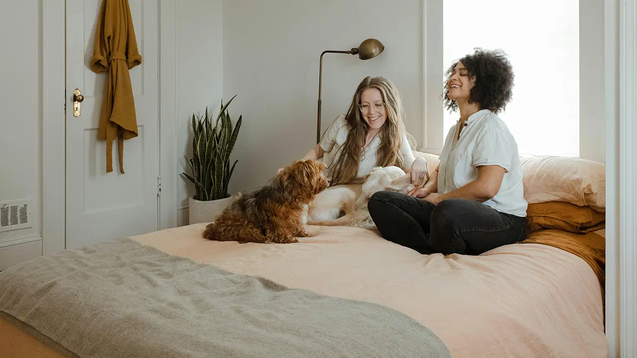 Key Factors in Choosing Your NDIS-Supported Living Provider Two NDIS participants with a dog on a bed smiling